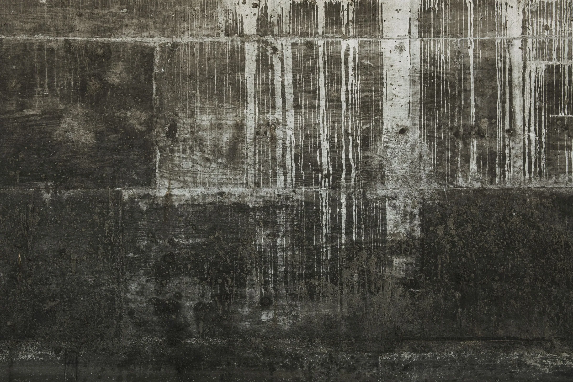 Concrete wall marked by long vertical water staining across its poured lifts