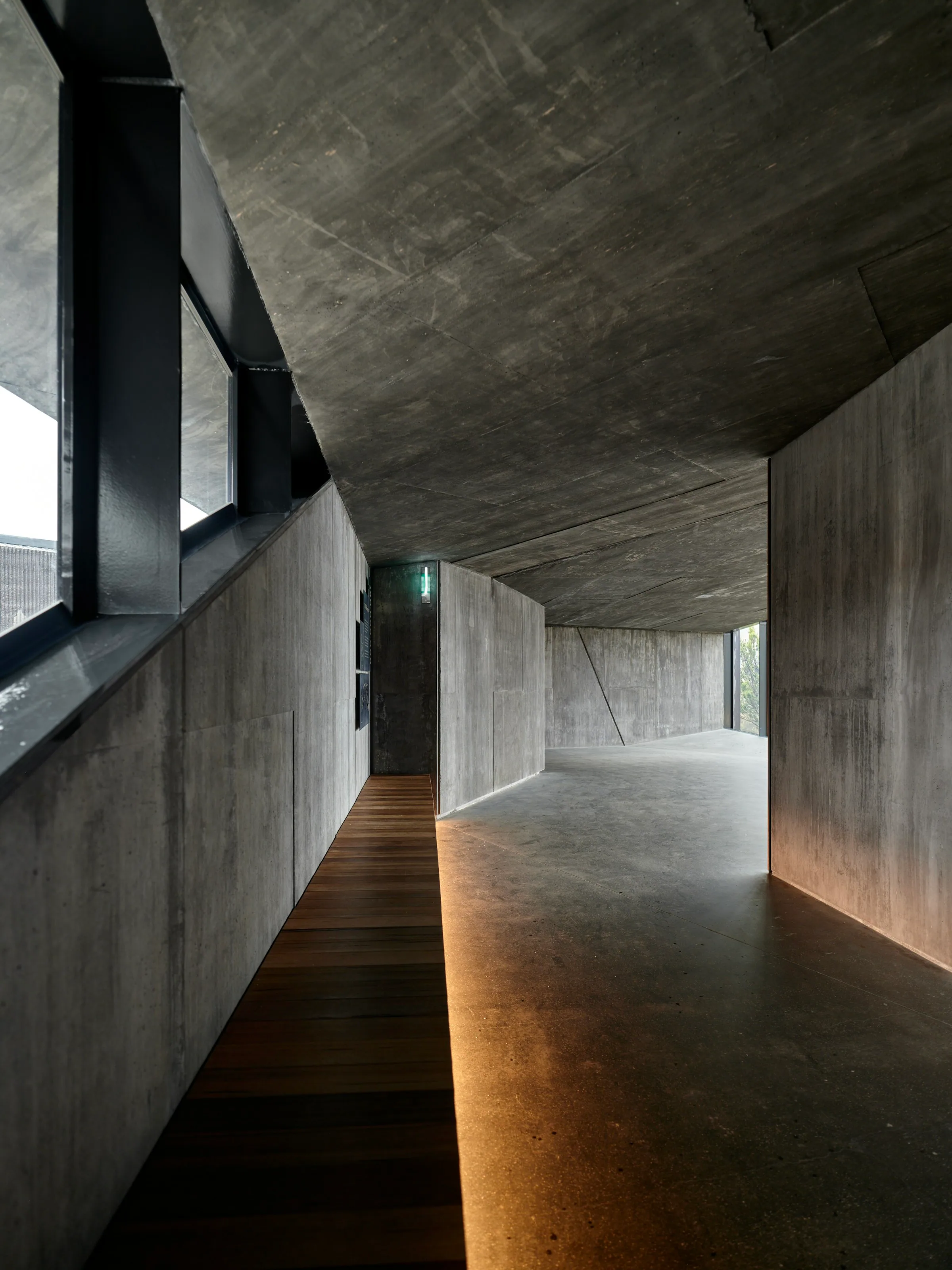 Timber walkway running through a concrete interior in low, even light
